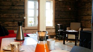 A wooden cabin interior with a dining table set for two, a coffee maker, and a window with a view of the outside. - Tradisjonell Rorbu i fiskeværet Ballstad (Vestvågøy)