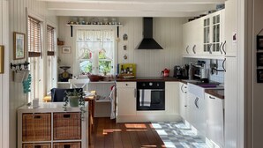 Una cocina amplia con armarios blancos, una campana extractora negra y un piso con diseño a cuadros.