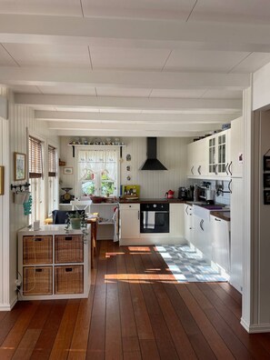 A spacious kitchen with white cabinetry, a black range hood, and a checkered floor pattern. - Nordlandshus ved havet på Reine, Lofoten (Moskenes)