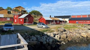 Un village côtier aux bâtiments rouges, avec un quai et une mer calme.
