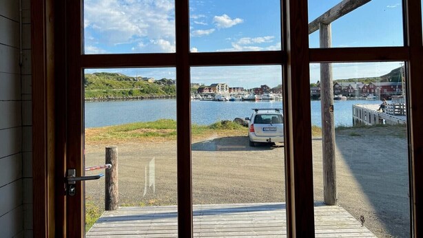 Une porte en bois donnant sur un port de plaisance, des bateaux et des bâtiments situés de l’autre côté de l’eau.