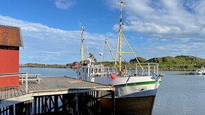 Un bateau était amarré à un quai, près d’un bâtiment rouge.