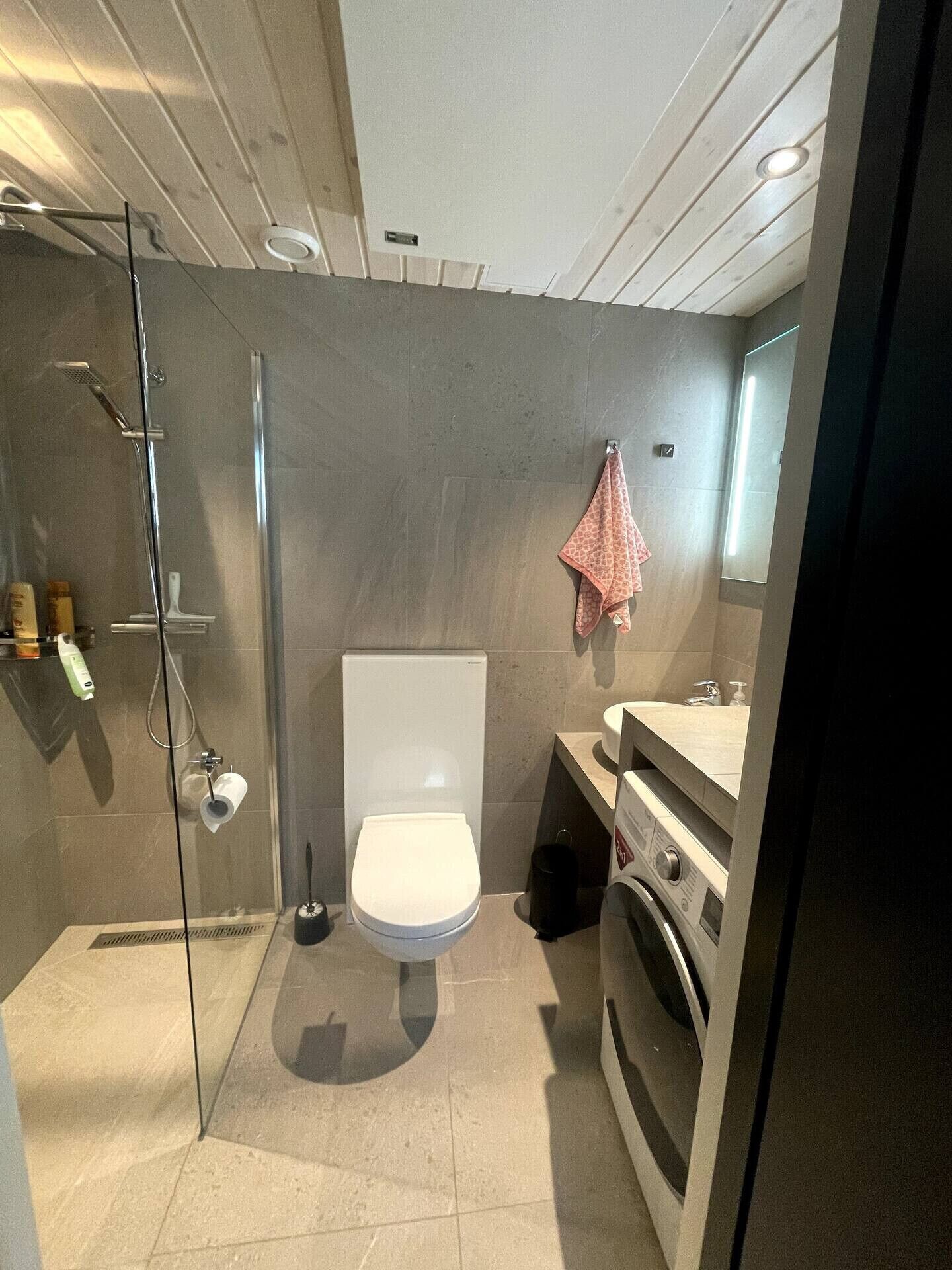 Ein modernes Badezimmer mit einer Duschkabine, einer Toilette und einem Waschbecken mit Spiegel.