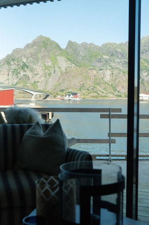 Blick aus einem Zimmer mit Fenster auf ein Gewässer, einen Berg und eine Brücke.
