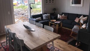Ein gemütliches Wohnzimmer mit einem Holzesstisch, einer Couch und einem schwarzen Herd.