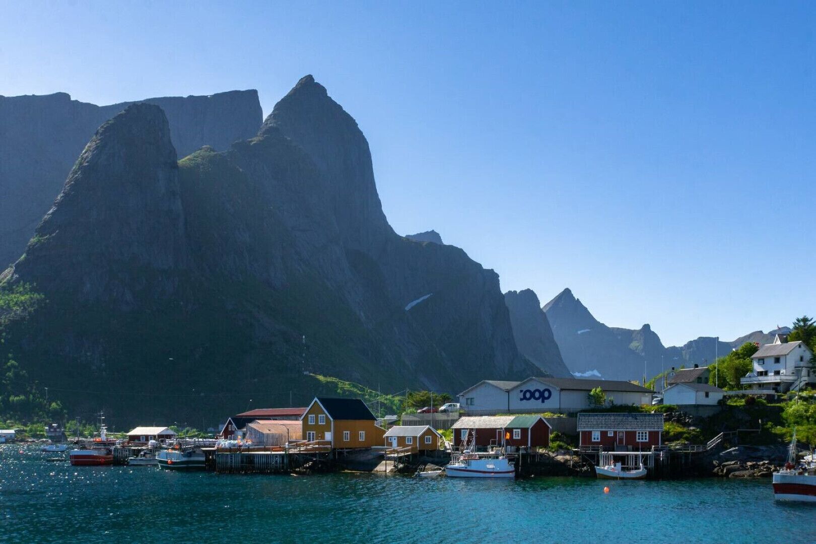 A coastal town with houses, boats, and a prominent mountain in the background.