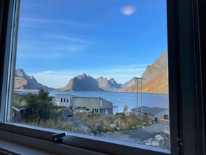 A coastal building with a view of mountains and a body of water. - House in Reine by the Fjord (Moskenes)
