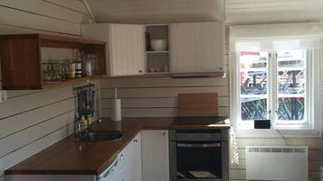Een koelkast, een oven, een waterkoker, kookgerei, borden en bestek