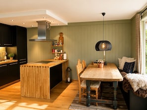 Een moderne keuken met een houten eiland, een eettafel met stoelen en een hanglamp.
