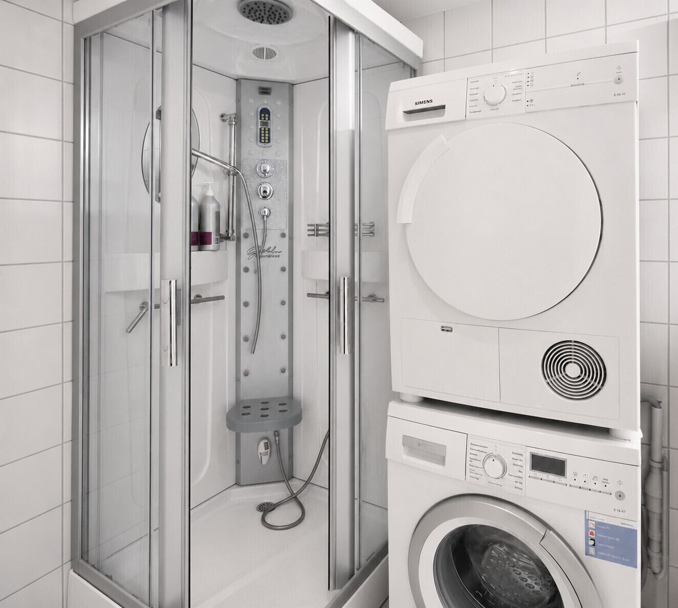 A modern bathroom with a glass-enclosed shower, a wall-mounted washing machine, and a toilet.