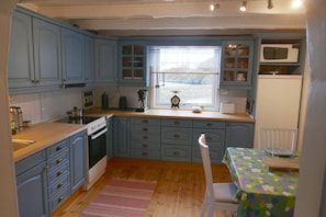 Una cocina con armarios azules, encimera de madera, una estufa y una ventana con vistas.