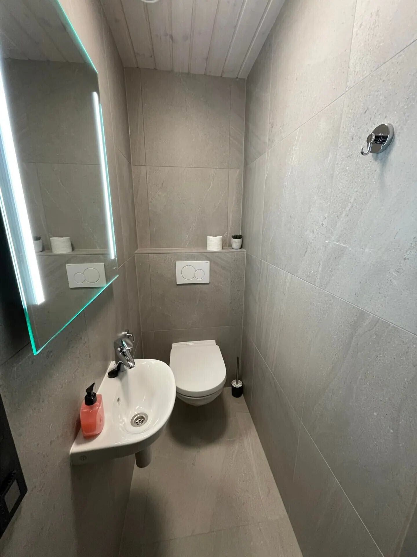 Ein kleines, modernes Badezimmer mit Waschbecken, Toilette und Spiegel.