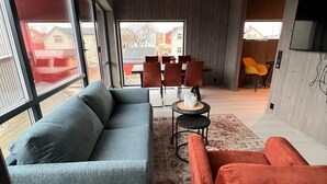 A modern living room with a sofa, a red armchair, a coffee table, and a TV mounted on the wall.