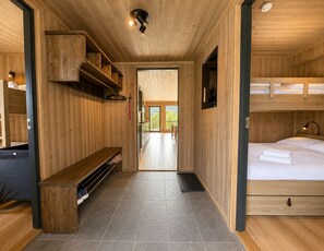 A wooden interior with a bench, a bed, and a view through a door.