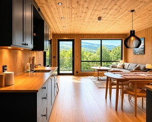A modern kitchen with wooden cabinets, a large island, and a dining area with a view of the mountains.