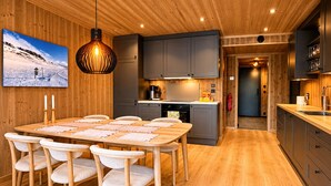 Une cuisine moderne avec des meubles en bois, un coin repas doté d’une table et de chaises en bois, et un luminaire suspendu.