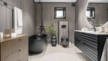 A modern bathroom with a large bathtub, a vanity with a mirror, and a wooden cabinet.
