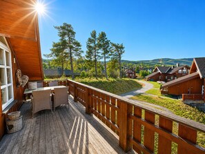 Eine Holzterrasse mit Tisch und Stühlen mit Blick auf ein Dorf mit Häusern und Bäumen.