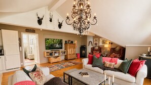 A cozy living room with a fireplace, a chandelier, and a television. - Sjelefred - stor leilighet med sentral beliggenhet (Hol)
