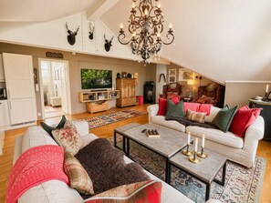 A cozy living room with a fireplace, a chandelier, and a television. - Sjelefred - stor leilighet med sentral beliggenhet (Hol)
