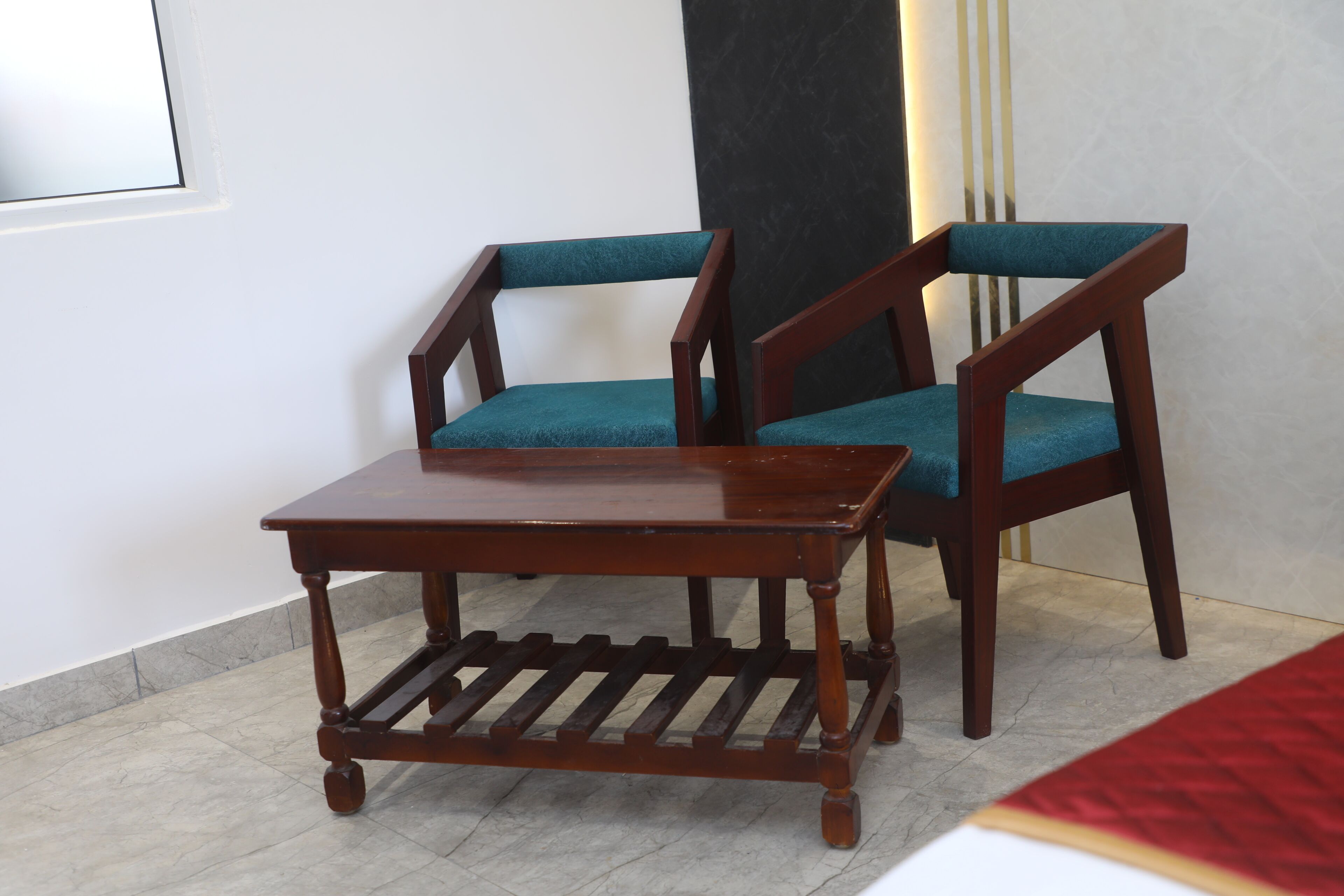 Een kamer met een houten tafel en twee stoelen met blauwgroene bekleding.