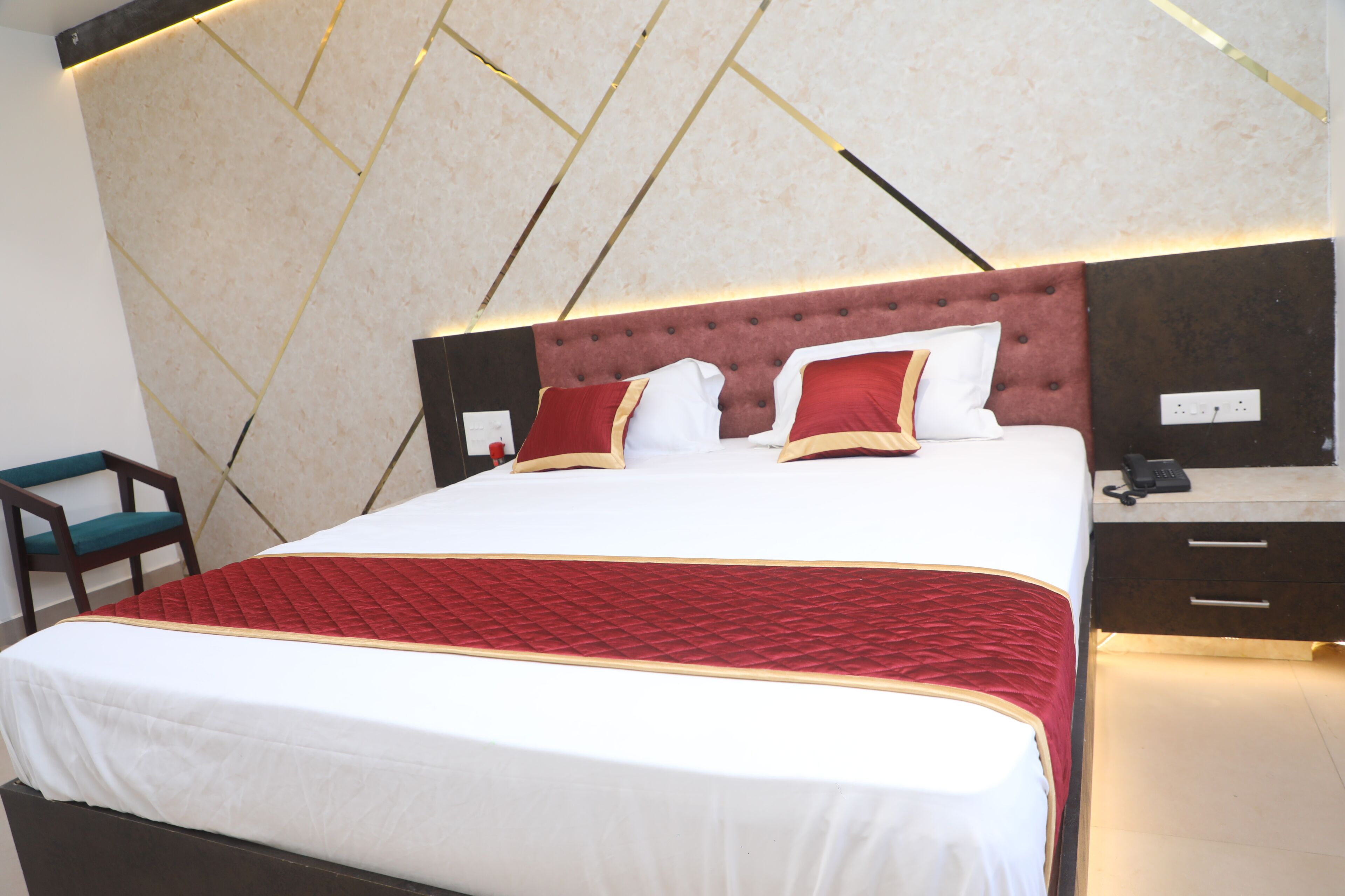 A neatly made bed with a red and white bedspread, a tufted headboard, and a bedside table with a phone.