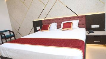 A neatly made bed with a red and white bedspread, a tufted headboard, and a bedside table with a phone.