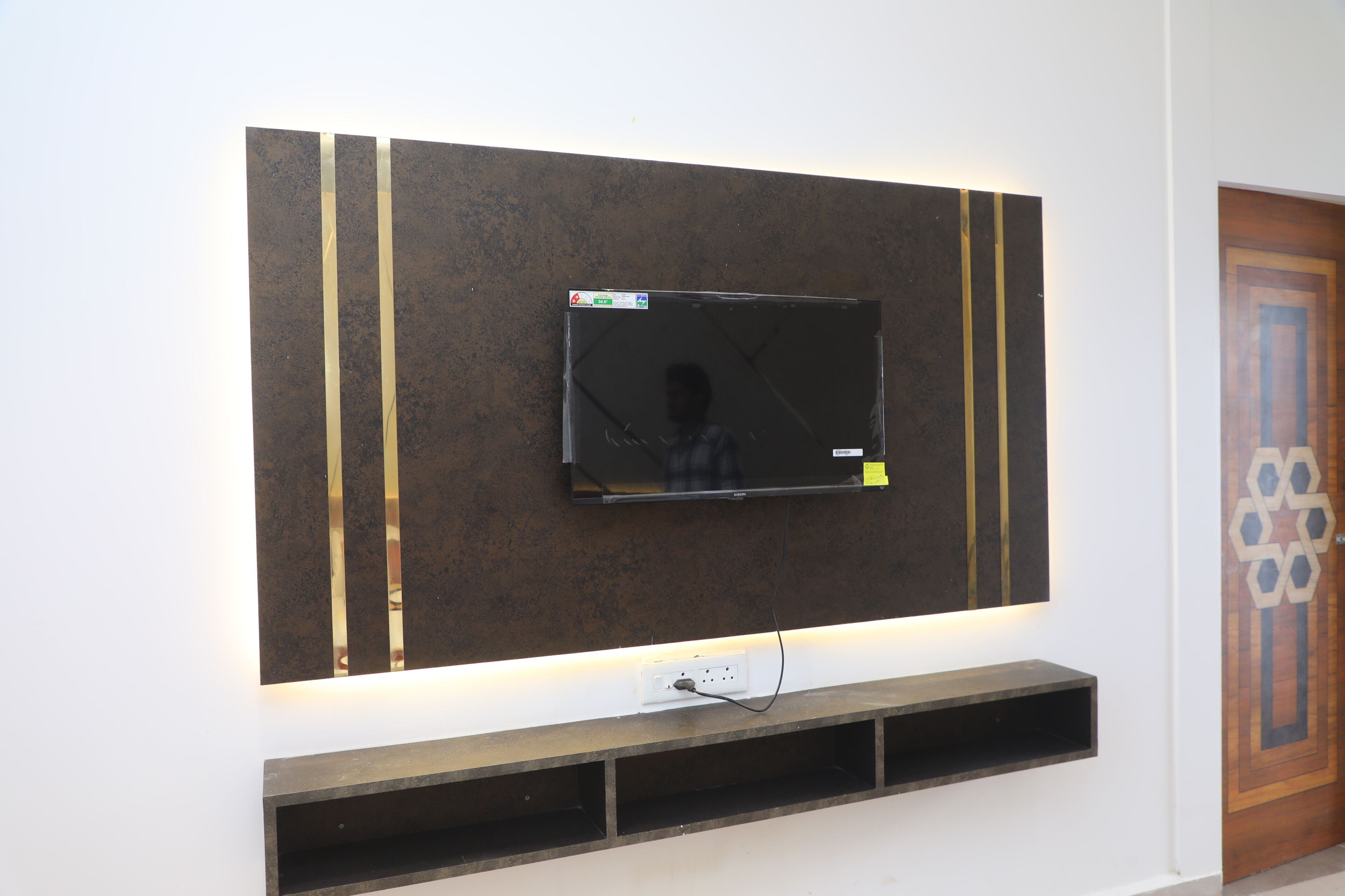 A flat-screen TV mounted on a wall with a shelf below it.