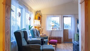 A cozy living room with a wooden floor, a large arched doorway, and a view of a mountain through the window.