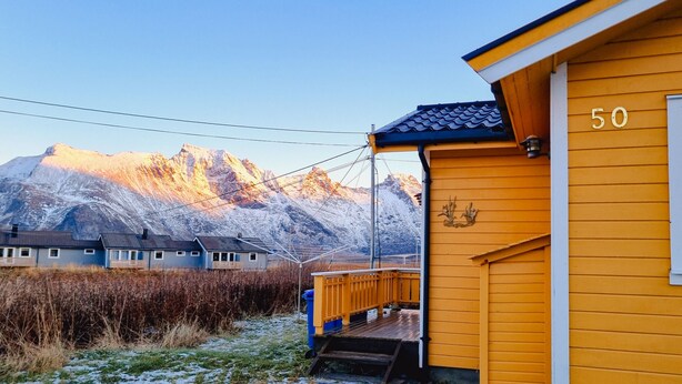 A yellow building with the number 50, a wooden deck, and a mountain in the background.