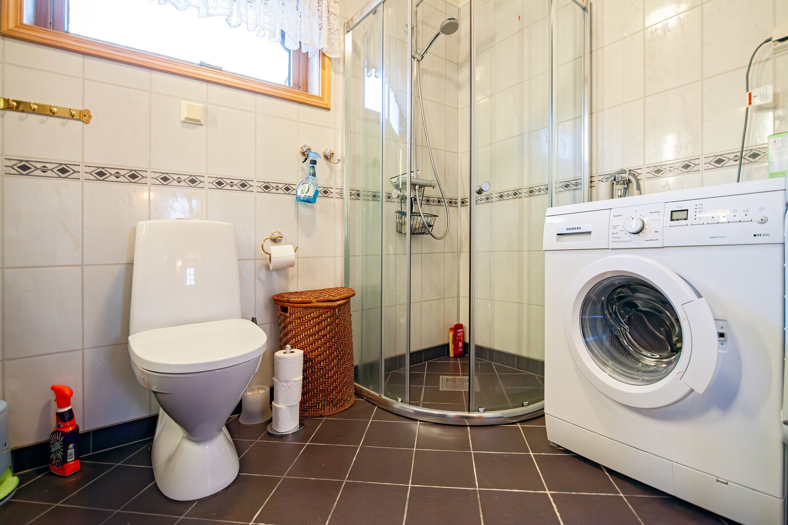 Ein Badezimmer mit Toilette, Dusche und Waschmaschine.