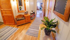 A hallway with wooden doors, a bench, a small table with a plant, a mirror, and a chalkboard menu.