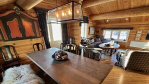 A wooden interior with a dining table, chairs, a sofa, and a fluffy dog. - Geilo centrum - cozy apartment - central location (Hol)