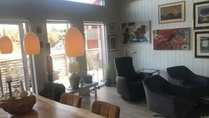 A spacious living area with a wooden dining table, black chairs, and a large window. - Amazing waterfront rorbu (free car-charging) (Vestvågøy)