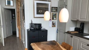 A kitchen with a wooden table, cabinets, and a microwave. - Amazing waterfront rorbu (free car-charging) (Vestvågøy)