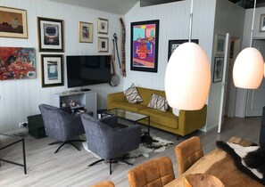 A modern living room with a sofa, chairs, a TV, and artwork on the wall. - Amazing waterfront rorbu (free car-charging) (Vestvågøy)