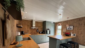Eine moderne Küche mit Holzwänden, einer zentralen Kochinsel, Barhocker und einer hängenden Pflanze.