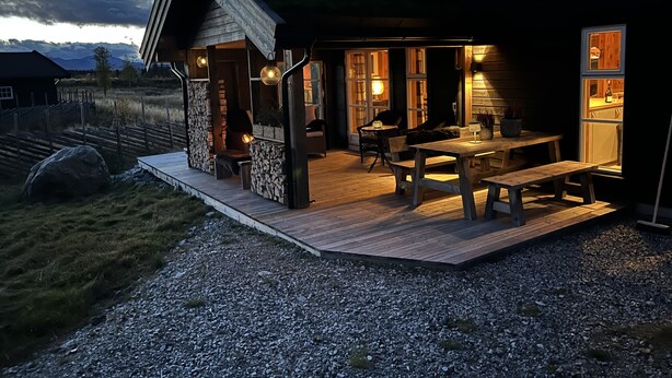 Ein Holzhaus mit überdachter Terrasse, Steinmauern und Kamin.