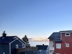 Ett bostadsområde med hus, en klar himmel och en sjö med berg i bakgrunden.