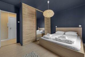 Quarto com cama, espelho, guarda-roupa e uma luminária pendente.