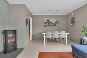 Uma sala de estar moderna com área de jantar, uma lareira a lenha preta e um quadro na parede.