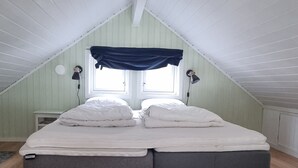 Une chambre avec un plafond de style industriel, un lit double, deux lampes de chevet et une fenêtre avec un rideau bleu.