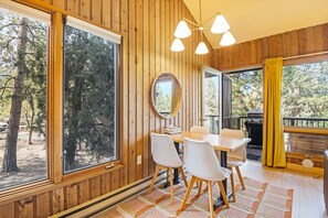 Um quarto com painéis de madeira, uma mesa de jantar, cadeiras, um espelho e uma janela grande.