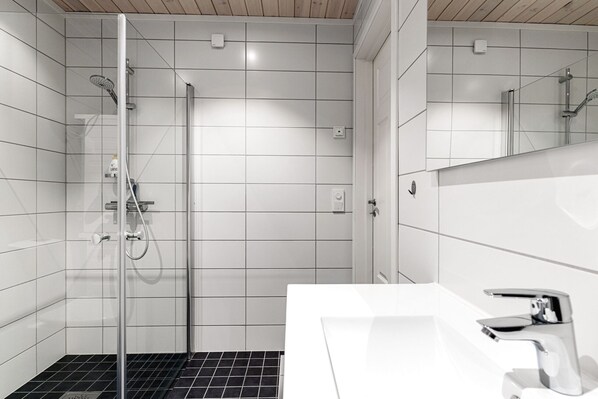 A modern bathroom with a glass shower enclosure, a white sink, and a mirror.