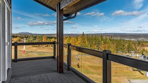 A wooden deck with a view of a ski lift and forested landscape.