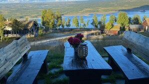Une table de pique-nique avec des bancs, un vase rempli de fleurs et une vue sur un lac et une forêt.