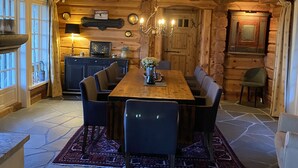 Un intérieur en bois comprenant une table à manger, des chaises, un lustre et un revêtement de sol en pierre.