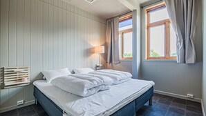 A bedroom with a bed, a bedside table, a lamp, and a window with curtains.