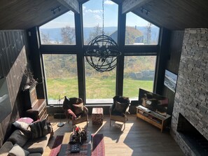 Ein geräumiges Zimmer mit großen Fenstern, einem Kamin und einem Fernseher.
