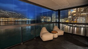 A modern interior with large windows, a balcony, and seating. - Premium Waterfront Apartment–Sea & Mountain View (Tromsø)